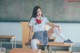 A woman sitting on top of a desk in a classroom.