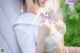 A woman in a white shirt and white lingerie sitting on a bench.