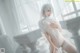 A woman in a white lingerie sitting on a bed.