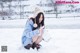 A woman kneeling down in the snow holding a snowman.