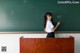 A young girl standing in front of a blackboard writing on it.