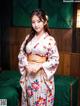 A woman in a kimono standing in front of a bed.