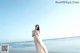 A woman standing on a beach next to the ocean.