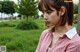 A woman in a pink shirt is standing in the grass.