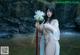 A woman in a white robe holding a white flower.